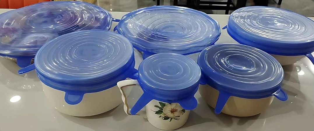 Five blue KAPIZAA stretch lids covering bowls and a mug on a kitchen counter